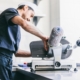 Side view of a young man slicing salami on an industrial grade slicer